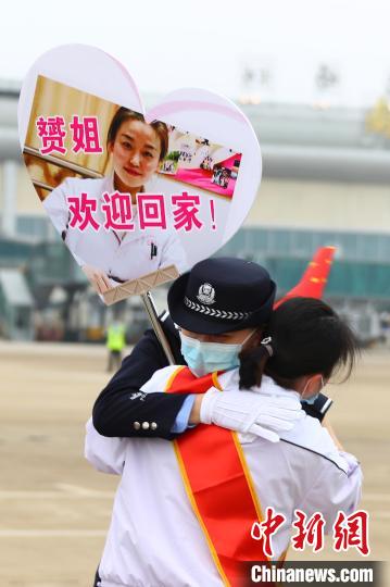 3月23日下午，一名医疗队队员与举着贴有自己照片牌子的民警妹妹相拥。　刘占昆 摄